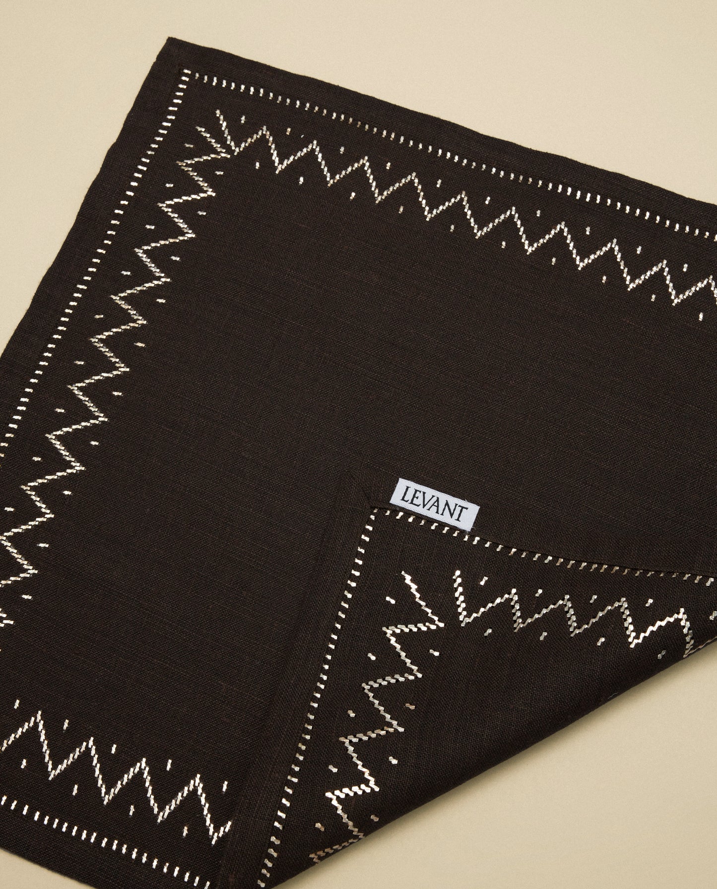 The Palmyra Sky Napkin, with silver embroidery on tobacco linen.